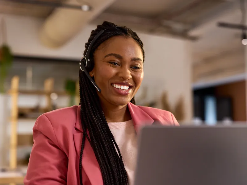Conseillère au téléphone avec un casque, souriante devant son ordinateur